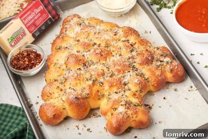 The full Christmas tree pull-apart bread, beautifully golden and garnished with herbs, presented on a baking sheet alongside a block of cheese.