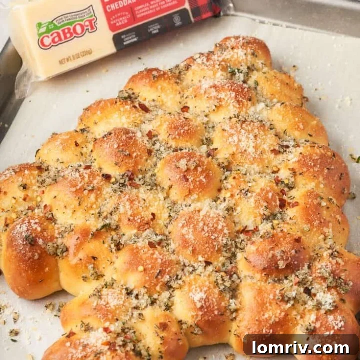 An image of a Christmas tree bread that is pull apart on a baking sheet with a block of cheese.
