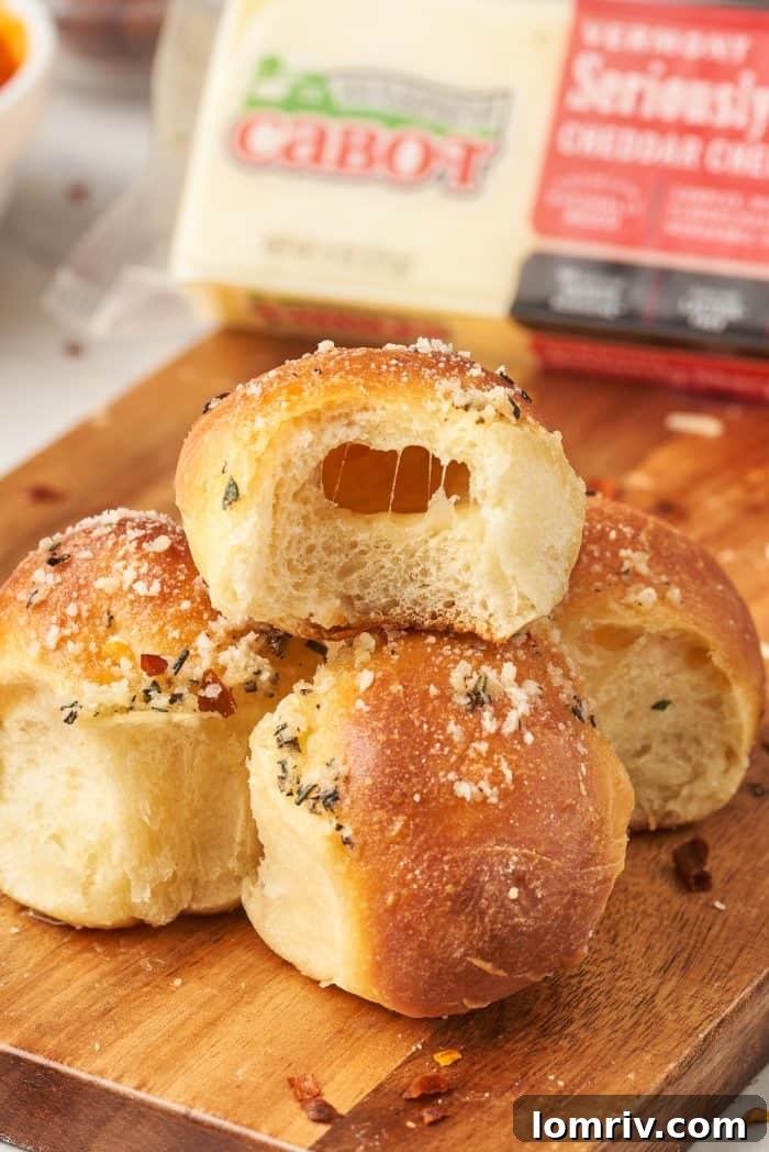 A close-up shot of a single dough ball, bitten into to reveal the melted cheese within, with a block of Cabot cheese hinting at the quality ingredients.