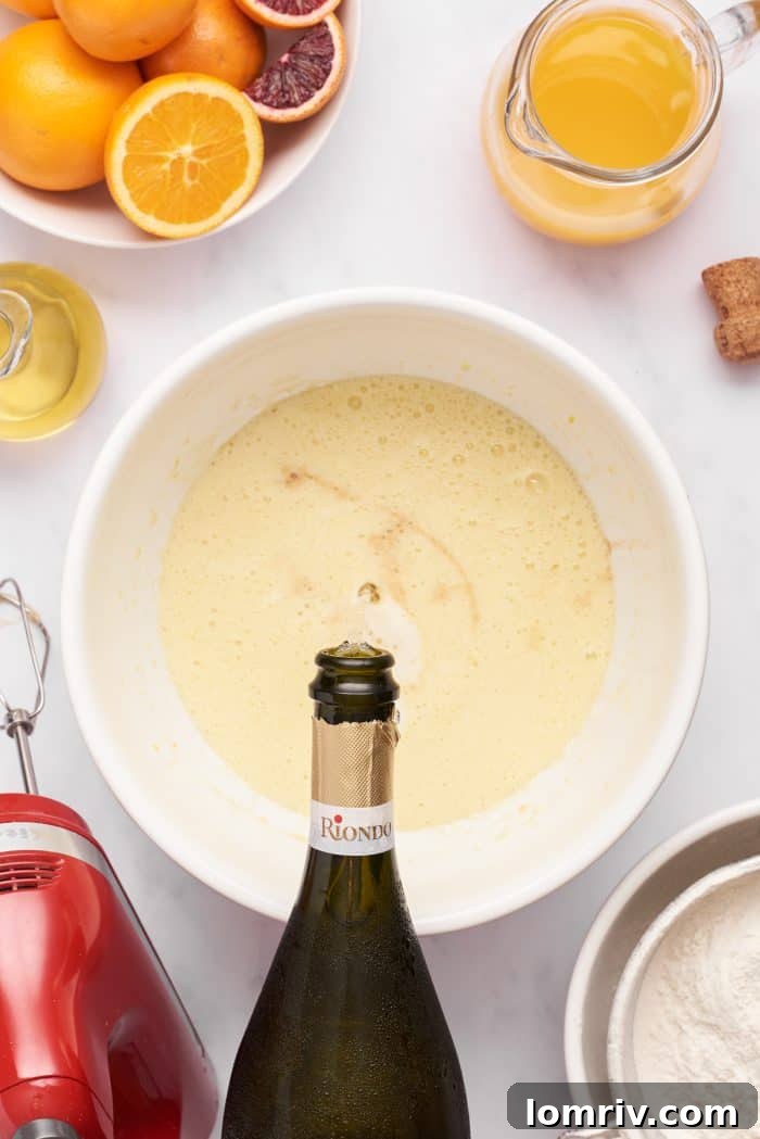 A bowl of cupcake batter, showing the addition of Prosecco and other wet ingredients, creating a light, bubbly mixture.
