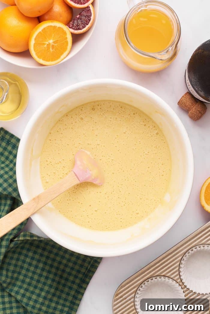 Smooth cupcake batter resting in a mixing bowl, with a wooden spoon partially submerged, indicating it's ready for baking.
