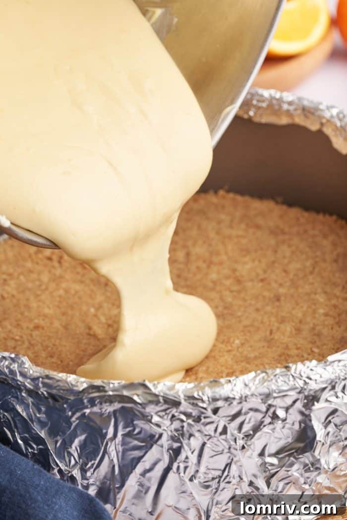 The smooth cheesecake batter being poured into the baked crust within the springform pan, ready for baking.