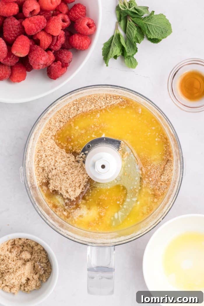 Melted butter added to graham cracker crumbs in a food processor, ready for mixing.