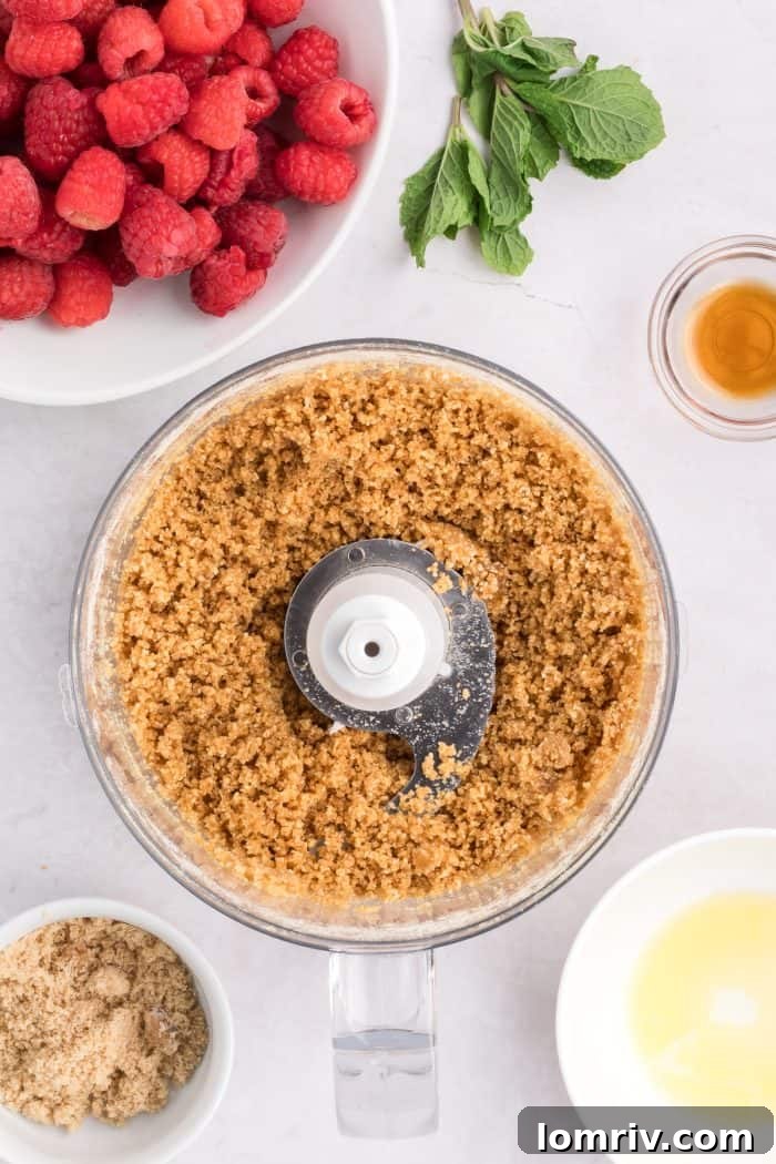 Ground graham cracker crumbs mixed with melted butter and sugar, showing a coarse sand texture.