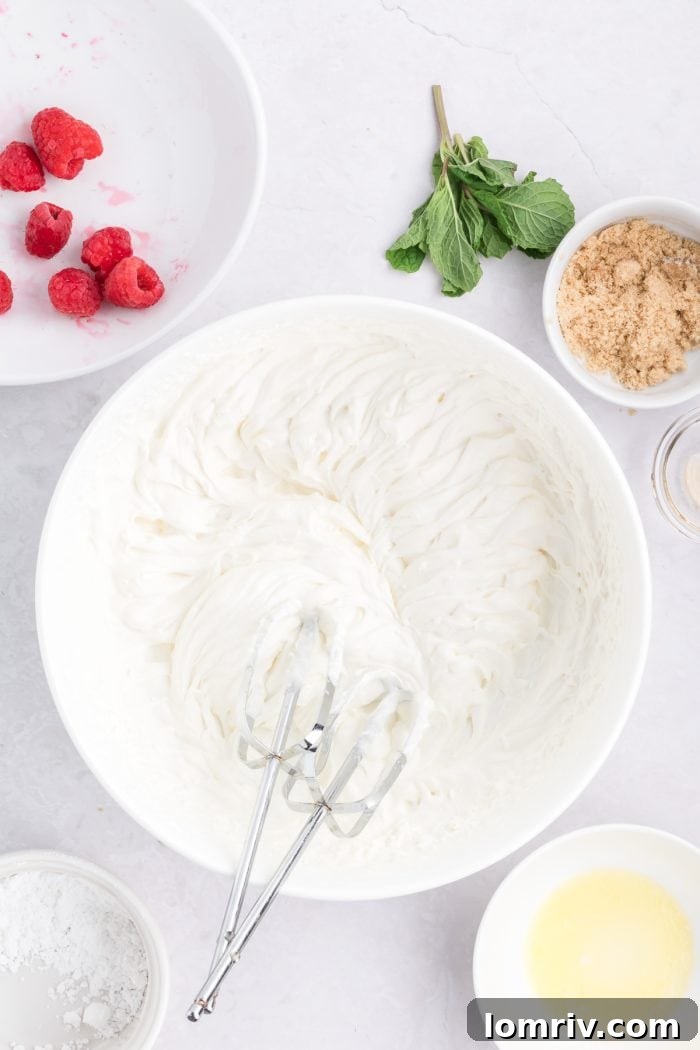 Heavy whipping cream being whipped to soft peaks in a white bowl with a hand mixer.