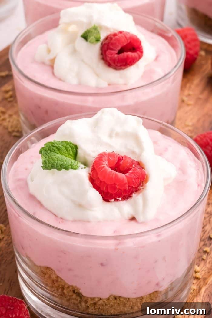 Close-up of a glass serving dish filled with creamy raspberry mousse and a spoon.