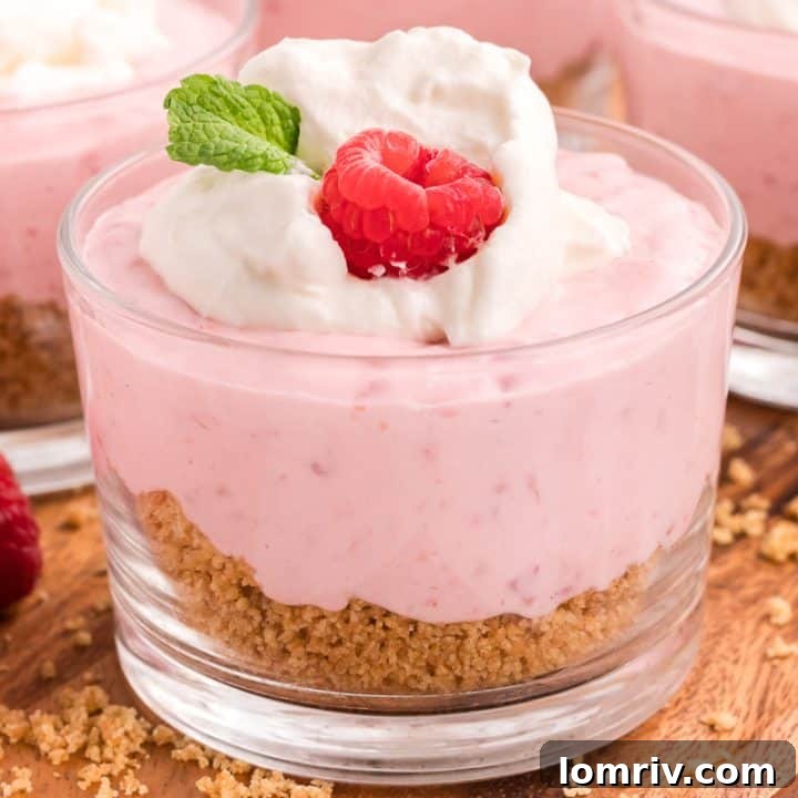 Three serving dishes of raspberry mousse on a wooden background.