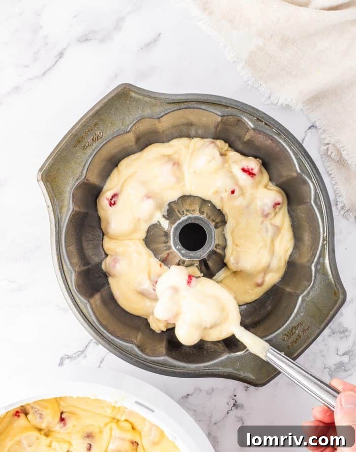 Cake batter being meticulously spooned into a meticulously prepared Bundt cake pan.
