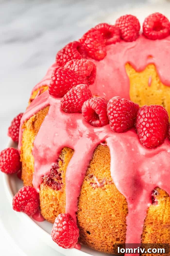 A finished bundt cake, beautifully decorated with an array of fresh raspberries, ready to be served.