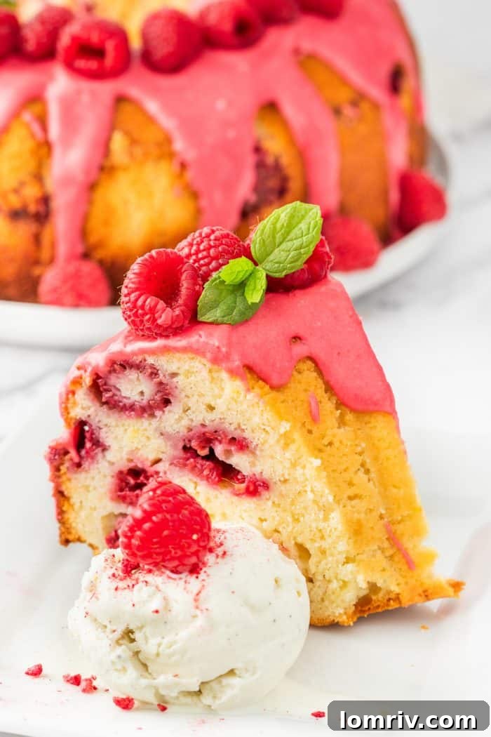A delectable slice of lemon raspberry bundt cake paired with a scoop of vanilla ice cream on a white plate.