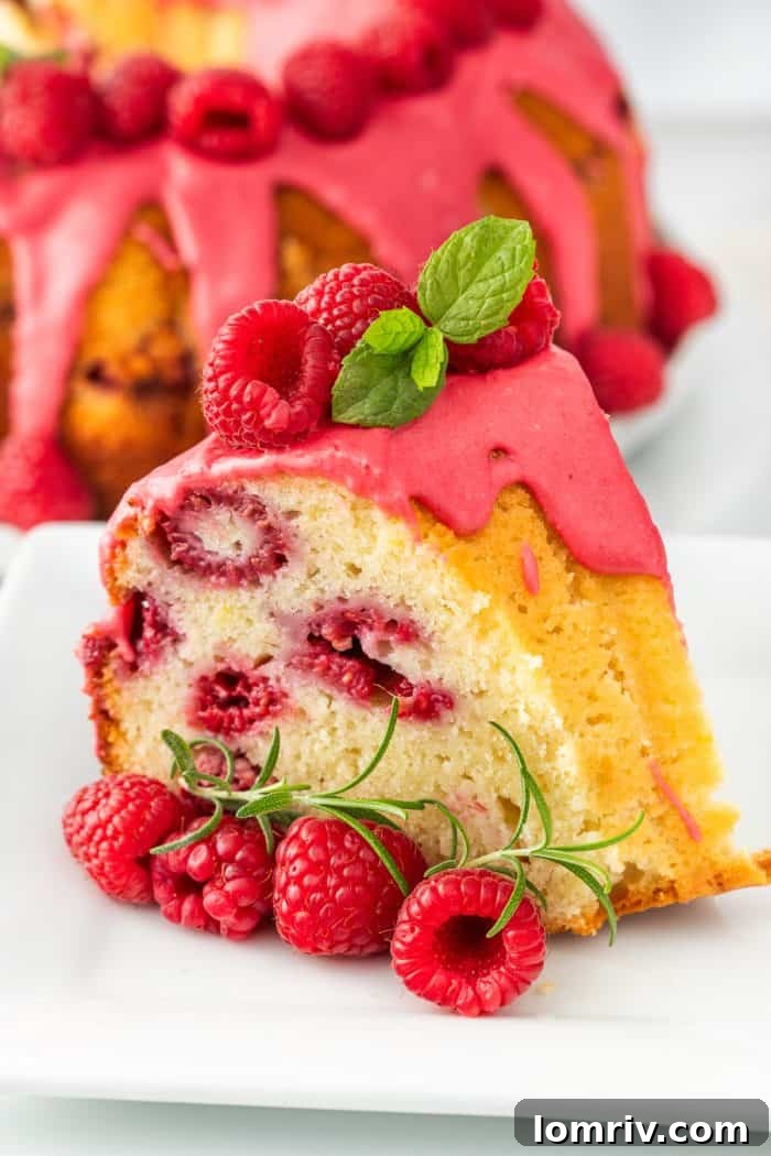 A slice of lemon raspberry bundt cake on a pristine white plate, garnished with fresh raspberries.
