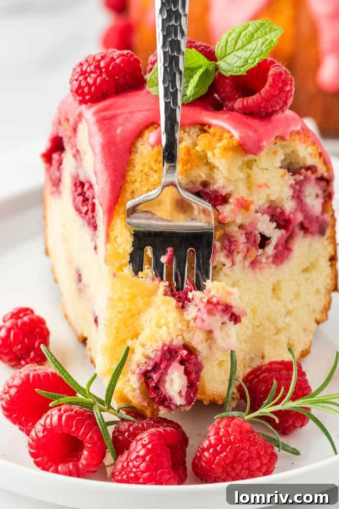 A fork piercing a slice of lemon raspberry bundt cake, poised for a delicious bite.