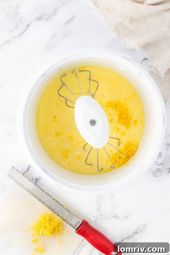 Additional wet ingredients being thoroughly mixed in a white bowl with a whisk.