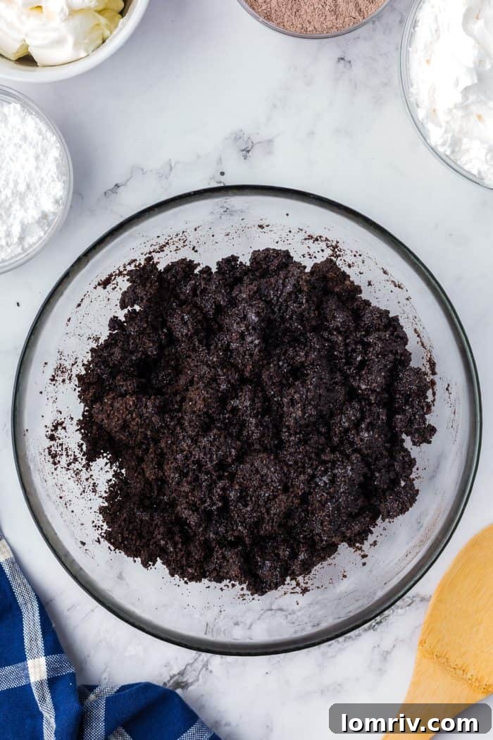 Oreo crumbs mixed with melted butter in a glass bowl.
