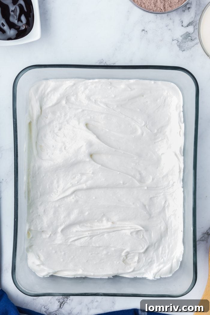 The cream cheese mixture spread over the Oreo crumb mixture in a glass dish.