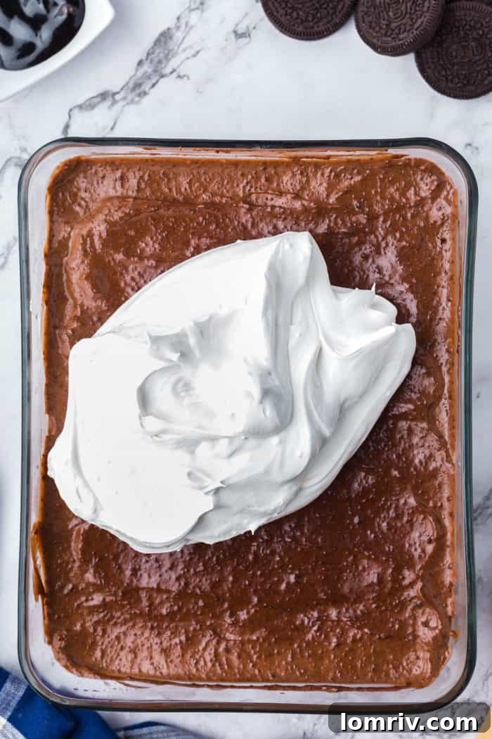 Cool Whip spread over the chocolate pudding mix in a glass dish.