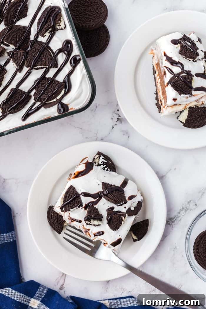An overview of the no bake Oreo layered dessert. Two slices are on white plate and there's an image of some of it in the baking tray.