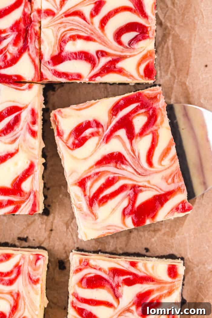 A delicious white chocolate raspberry cheesecake bar being carefully lifted with a spatula, with other bars visible in the background.