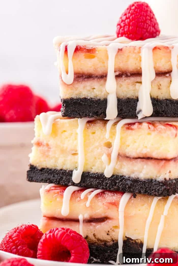 A perfectly arranged stack of three white chocolate raspberry cheesecake bars, highlighting their beautiful layers and tempting appearance.
