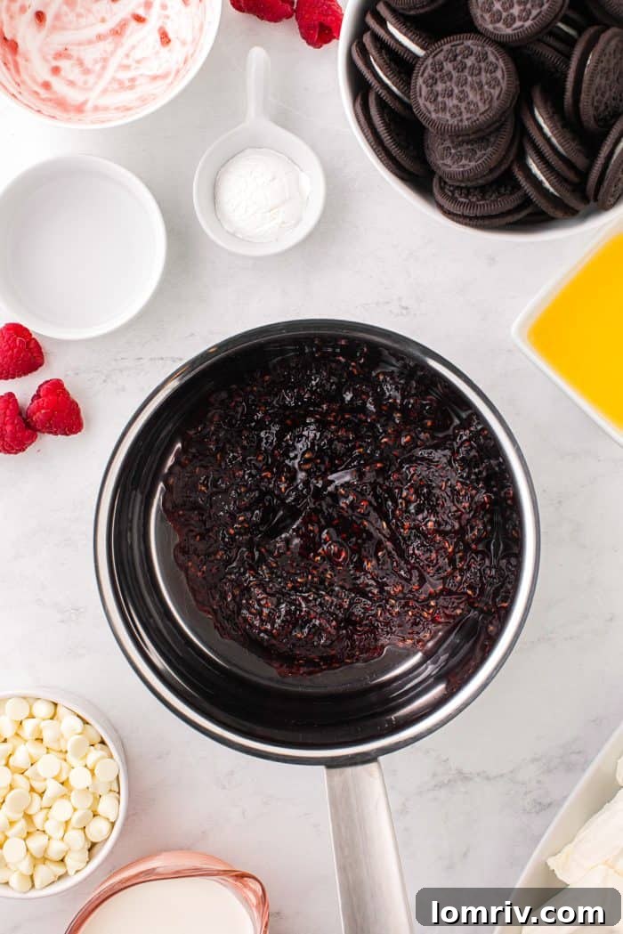 A saucepan filled with simmering raspberry preserves and water, surrounded by bowls of other ingredients for the cheesecake bars.