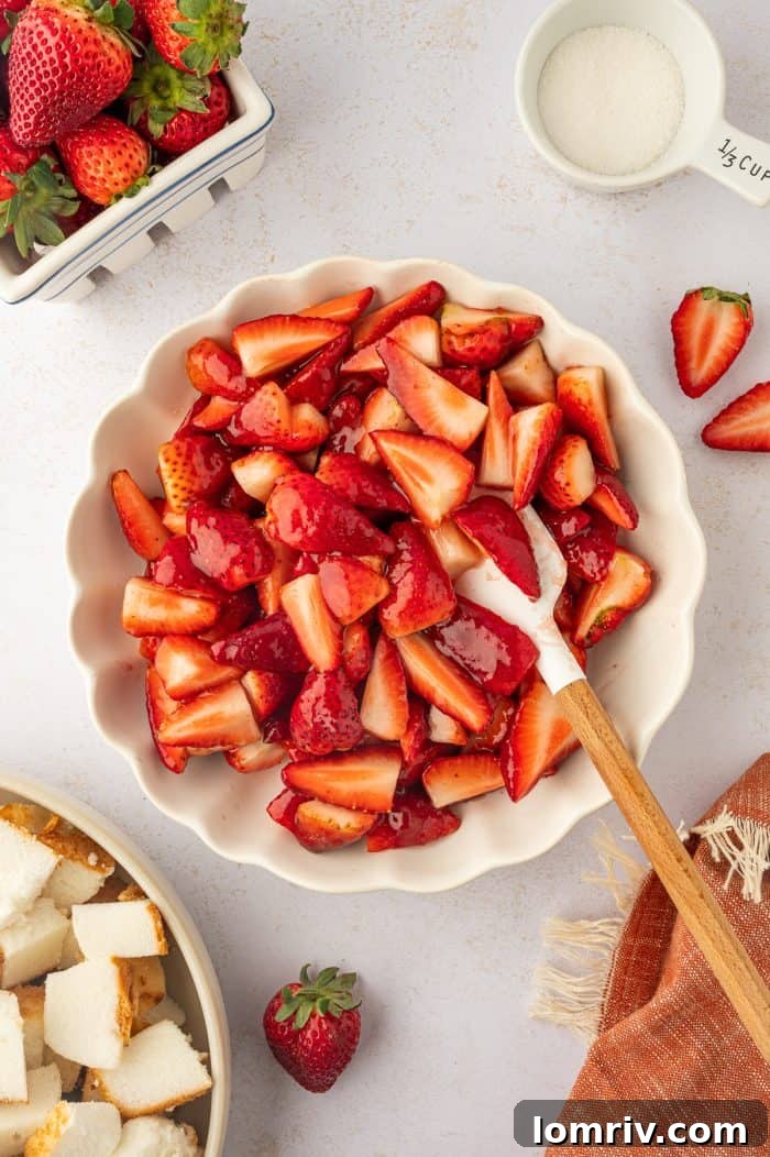 A bowl of sliced strawberries mixed with sugar and strawberry preserves, creating a beautiful, glossy fruit mixture.