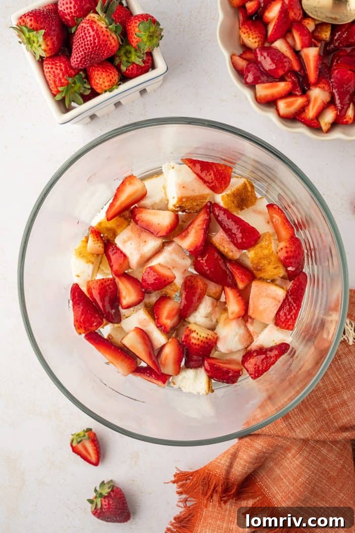 A layer of vibrant, juicy strawberries spread over the cake base in a trifle bowl, adding color and flavor.