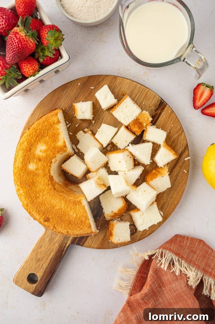 Cubed angel food cake arranged neatly on a round wooden cutting board, ready for trifle assembly.