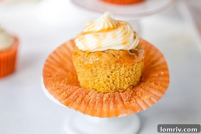 An array of pumpkin cupcakes, some unfrosted, others with a dollop of creamy caramel frosting, showcasing their inviting texture.