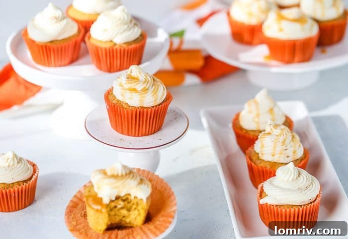 A stack of beautifully frosted pumpkin spice cupcakes, with a rich caramel drizzle cascading over the cream cheese frosting.
