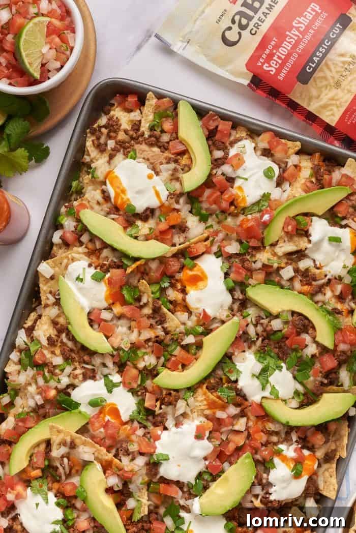 Baked sheet pan nachos with pico de gallo and sliced avocado.