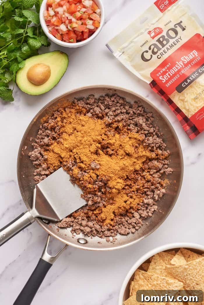 Cooked ground beef with taco seasoning added in a skillet.