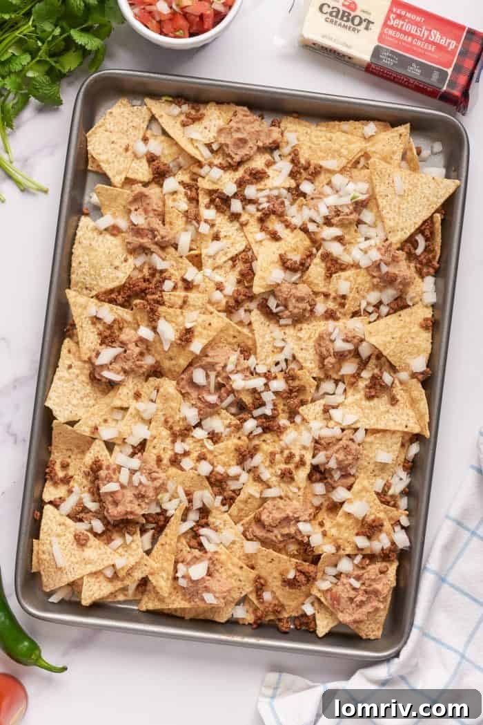 Tortilla chips with a layer of ground beef, refried beans, and onions.