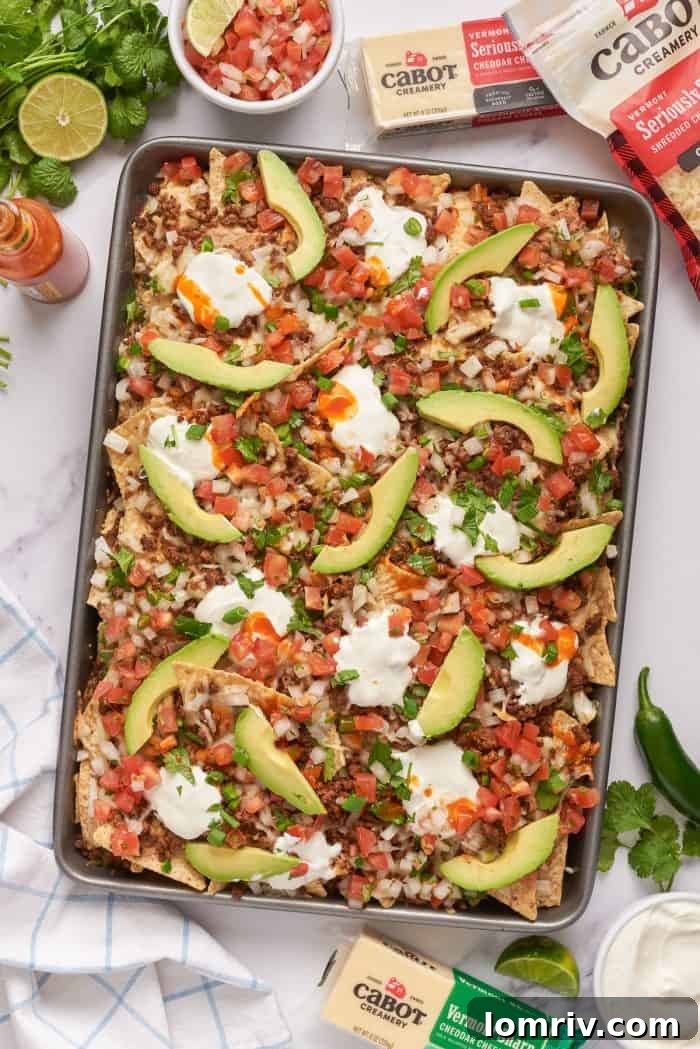 Baked sheet pan nachos with pico de gallo and sliced avocado.