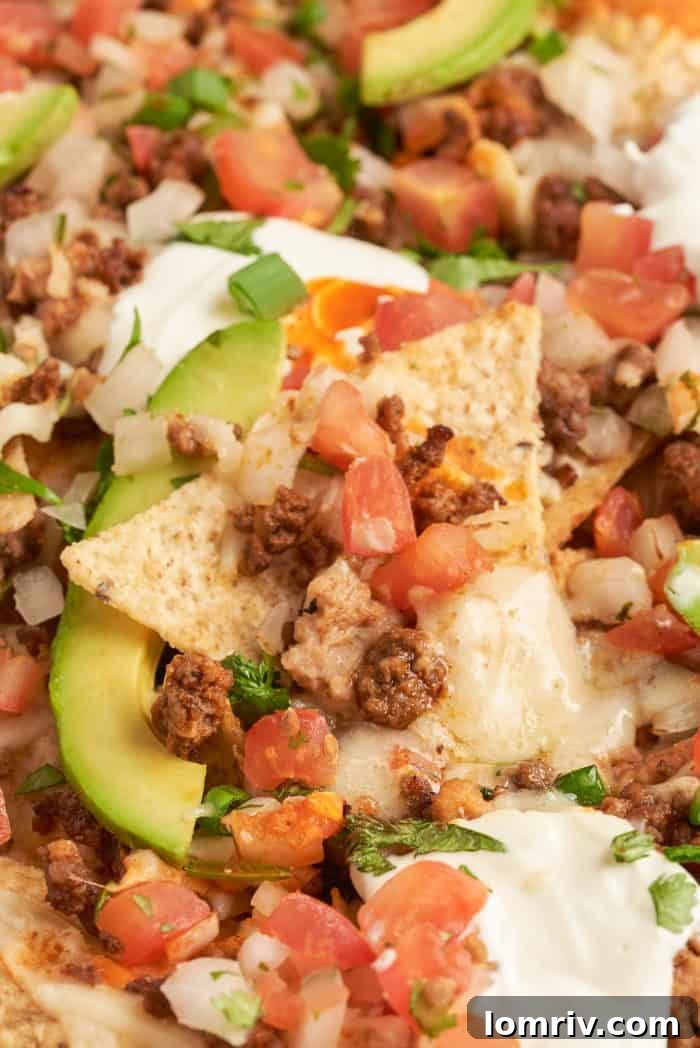 Baked sheet pan nachos with pico de gallo and sliced avocado.