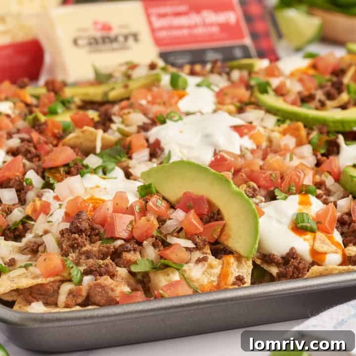 An upclose image of sheet pan nachos showing the sliced avocados and tortilla chips with melted cheese.