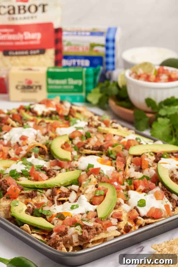 Baked sheet pan nachos with pico de gallo and sliced avocado.