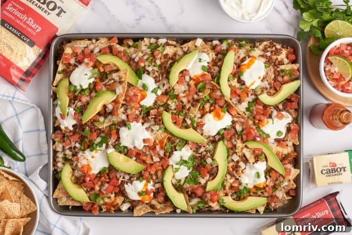 Baked sheet pan nachos with pico de gallo and sliced avocado.