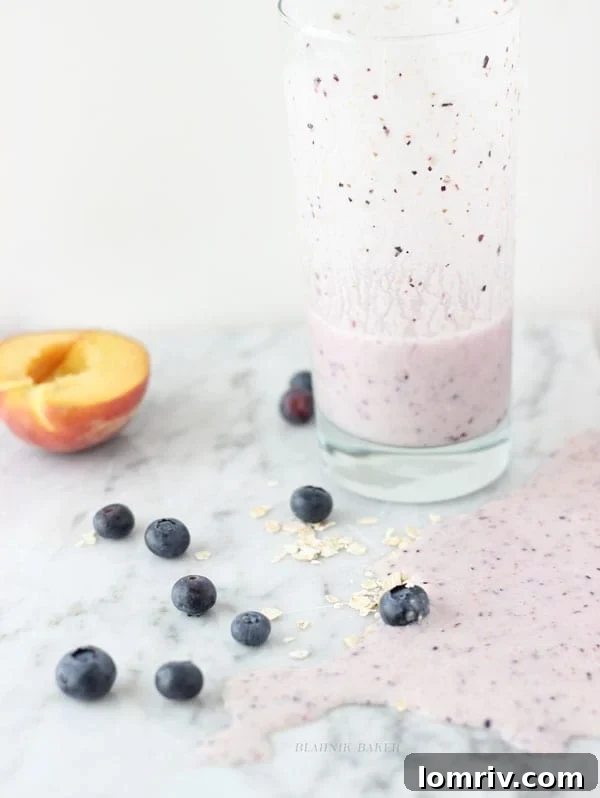 Delicious and healthy Peach Blueberry Oatmeal Smoothie in a glass, garnished with fresh fruit