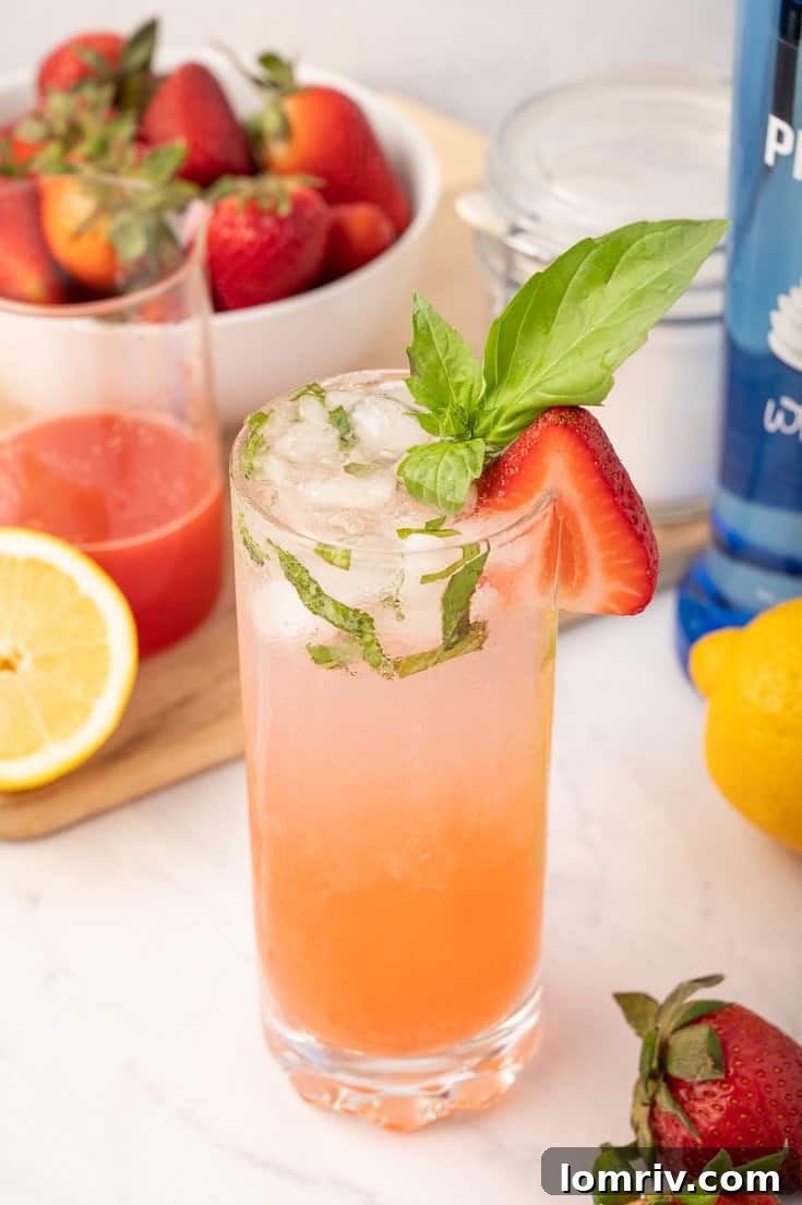 Glass of Strawberry Basil Sparkler with fresh strawberries and basil