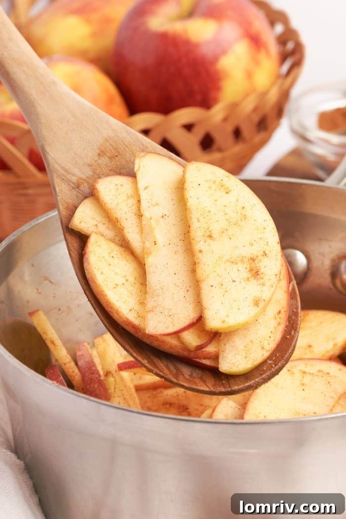 A wooden spoon holding sliced apples that have been coated in cinnamon and sugar.