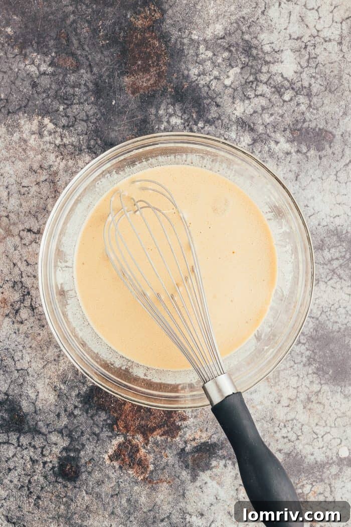 The wet ingredients in a glass bowl with a whisk.