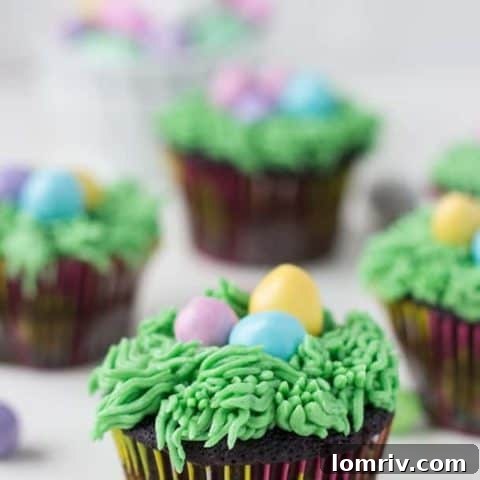 Cute Easter chocolate cupcakes decorated with green frosting grass nests and mini speckled candy eggs.