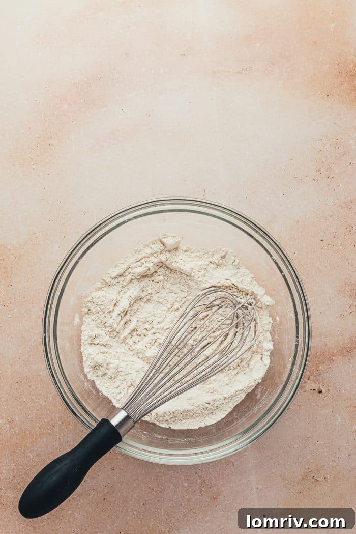 A glass bowl containing all-purpose flour, ready for whisking with other dry ingredients.