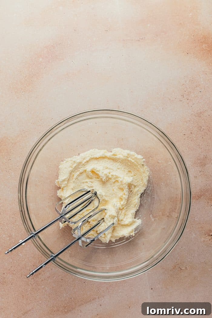 A glass bowl holding creamy, white sour cream, perfectly at room temperature and ready to be added to the cake batter.