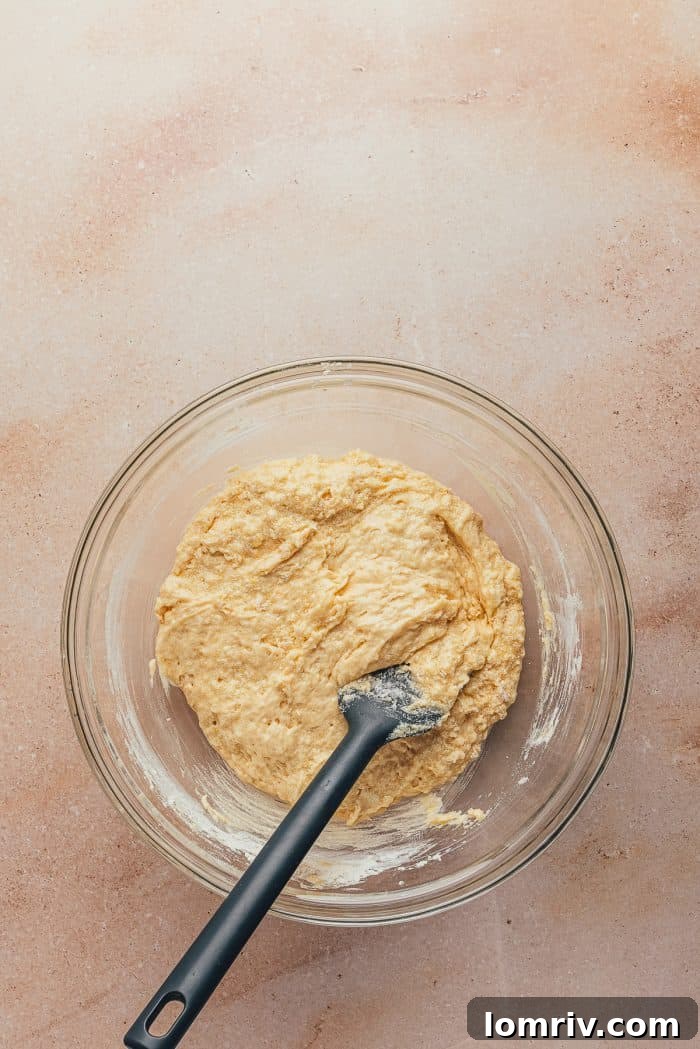 A glass bowl containing the velvety cake batter, exhibiting its creamy texture before the blueberries are folded in.