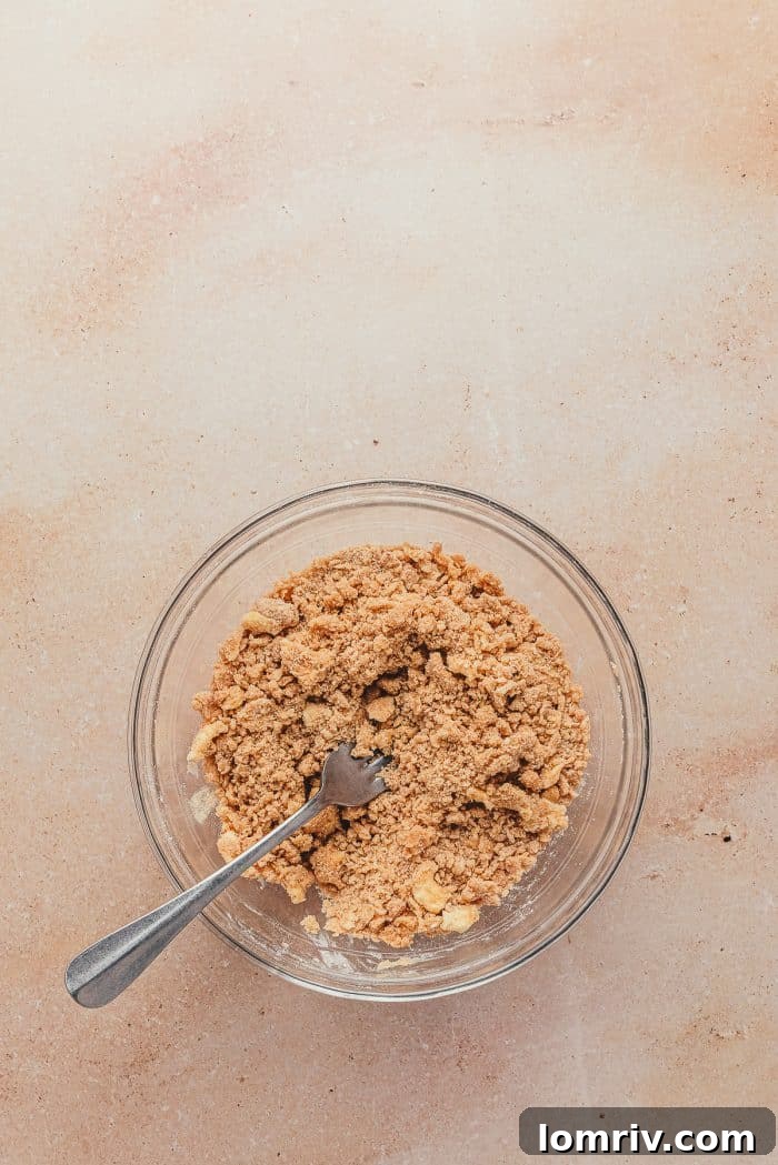A clear glass bowl containing the dry ingredients for the crumble topping, awaiting the addition of butter.