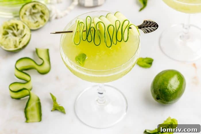 Three Cucumber Basil Gimlets, with the foreground drink elegantly garnished with a cucumber ribbon and basil, hinting at a lively gathering.