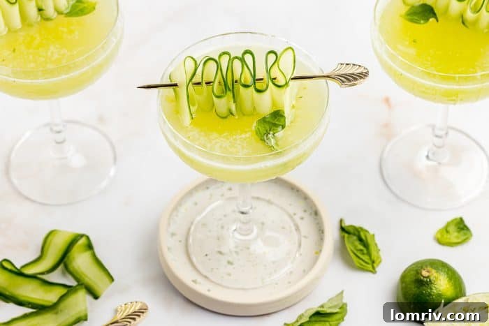A trio of Cucumber Basil Gimlets, with one prominently garnished with a cucumber ribbon, suggesting a celebratory atmosphere.