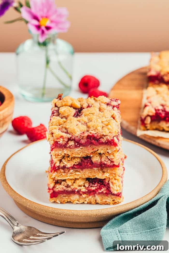 A stack of three raspberry crumble bars on a white plate.