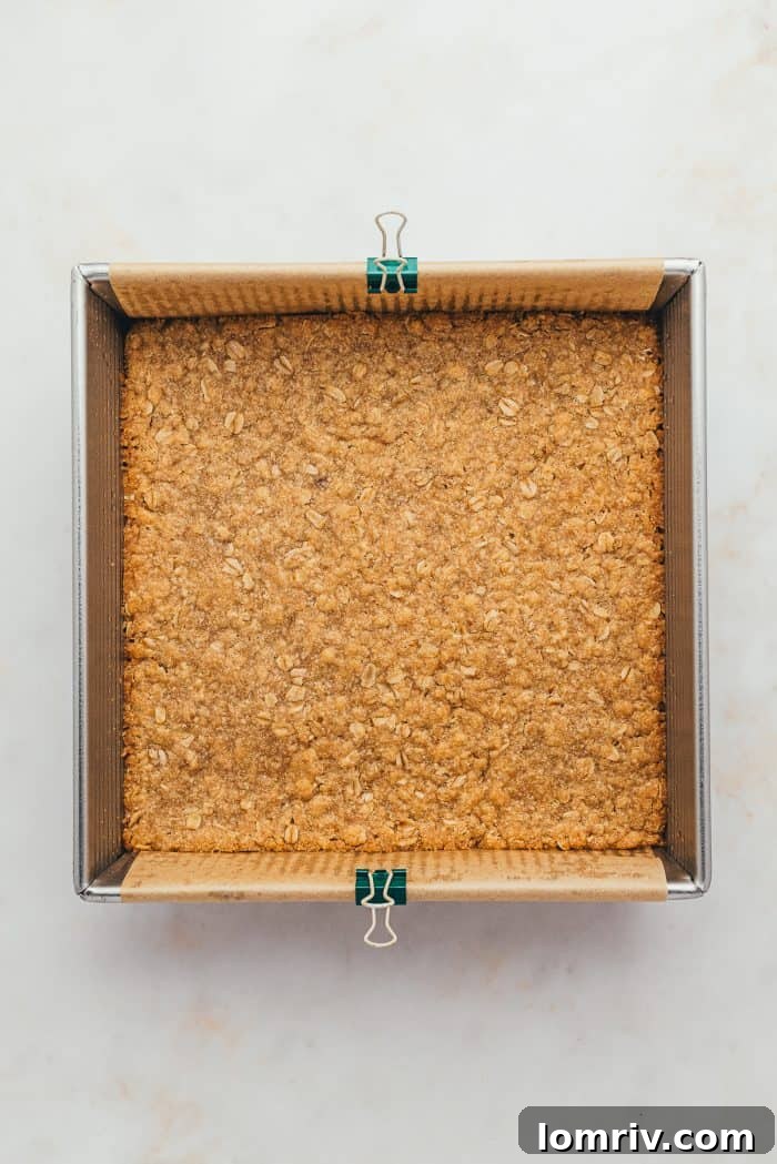 A baking tray lined with parchment paper and the baked bar crust.